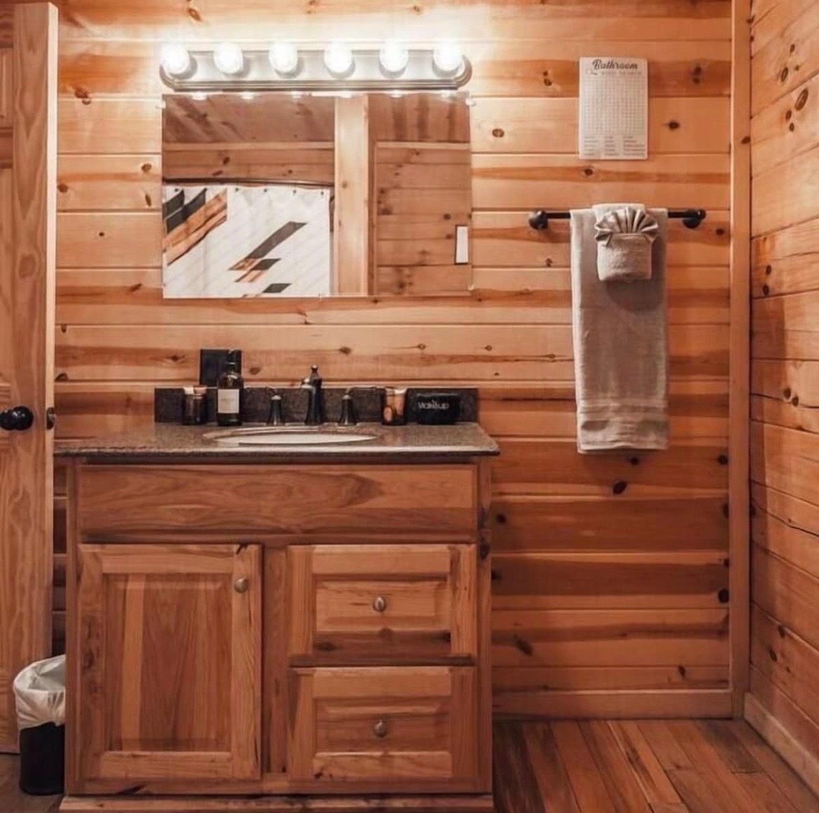 Bathroom vanity with granite top and wood-paneled walls