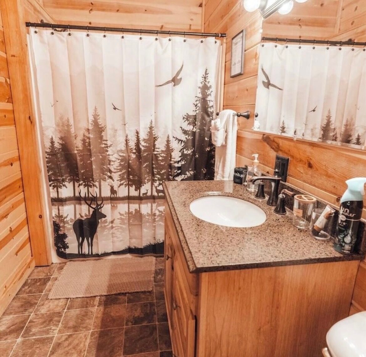 Bathroom with a forest-and-deer shower curtain and granite vanity