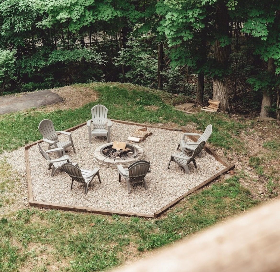 Gravel fire pit circled by Adirondack chairs in summer