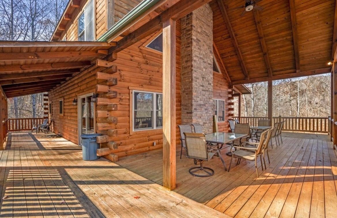 Wraparound covered deck with outdoor dining tables and brick chimney