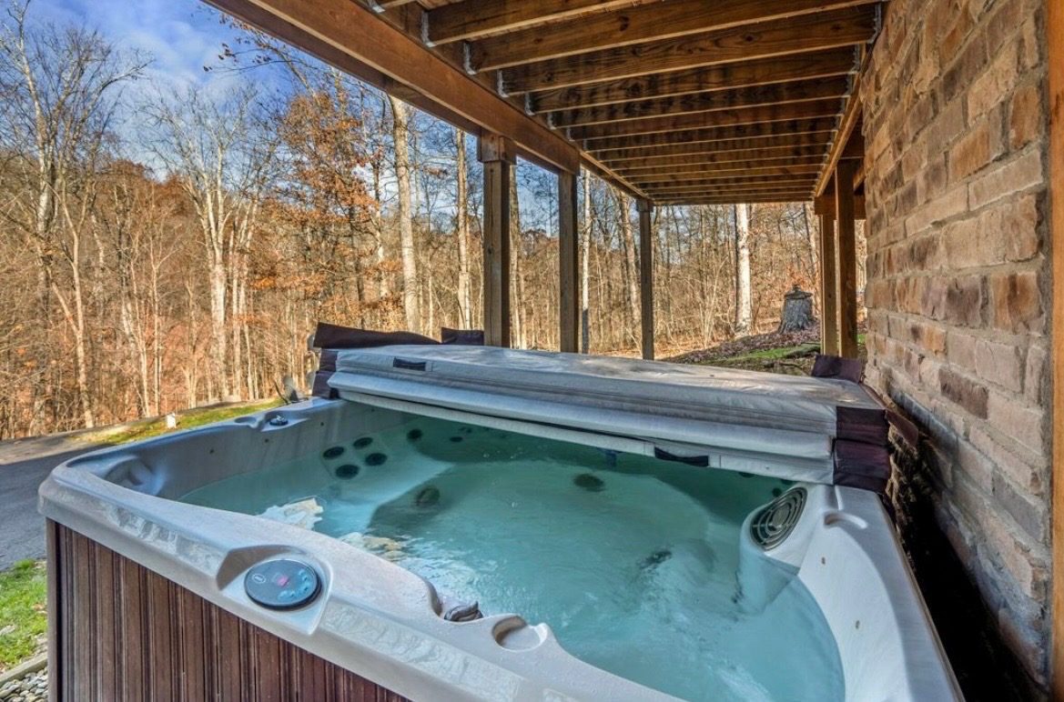 Covered private hot tub beside the lodge's stone wall