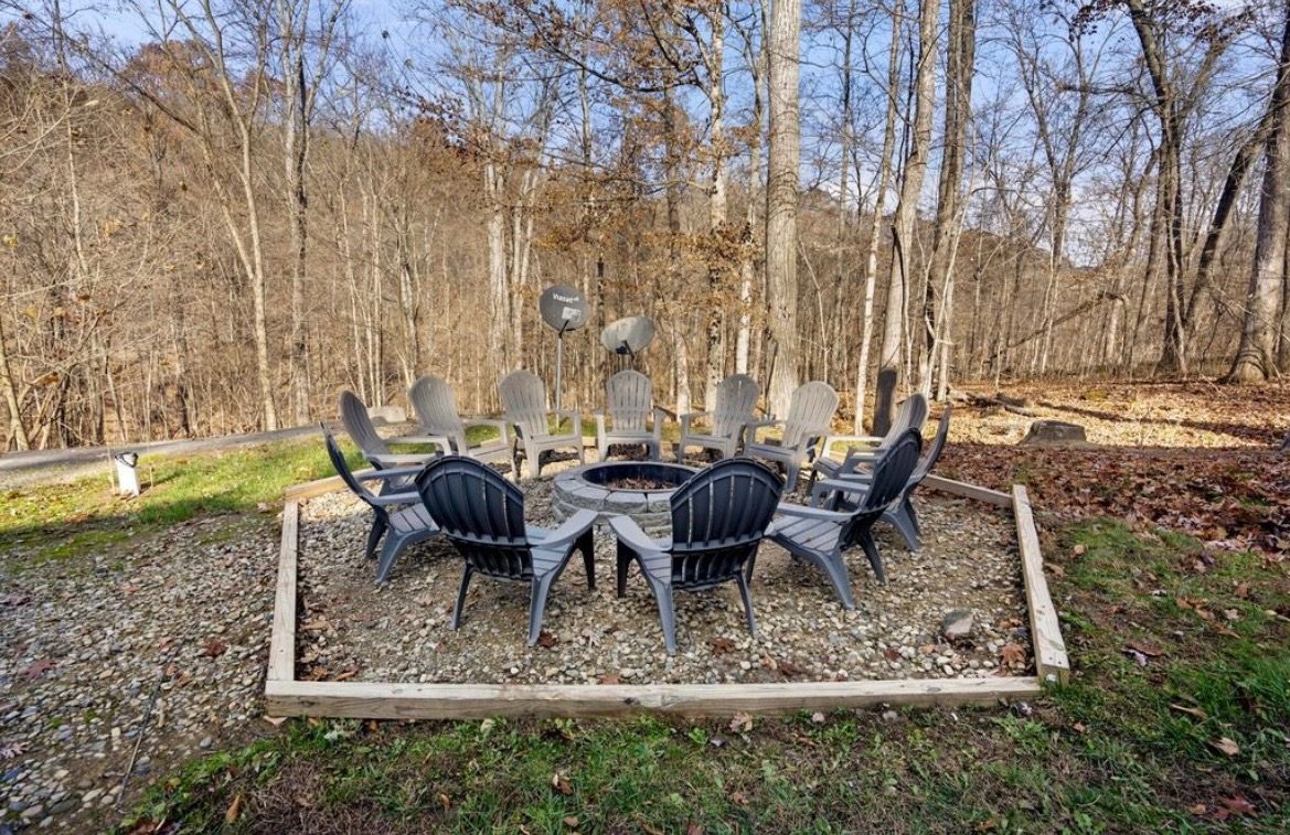 Fire pit with Adirondack chairs and fall woods behind