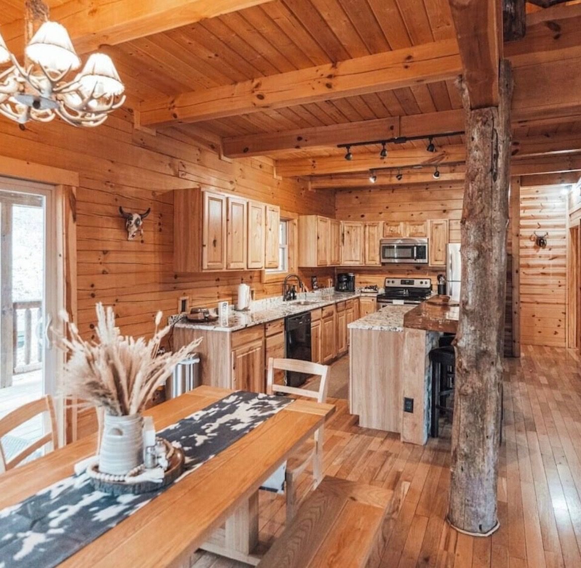 Dining table with bench seating opening into the kitchen and a log support post