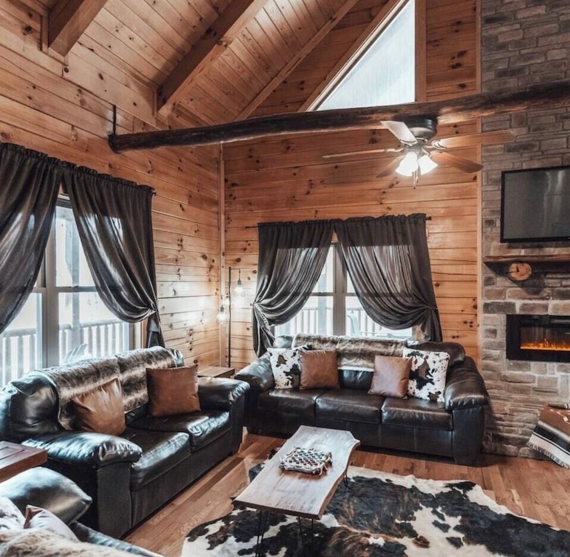 Living room with leather sofas, cowhide rug and stone electric fireplace