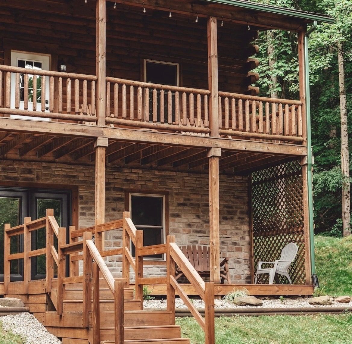 Two-story covered porches with log railings and stairs to the lower patio