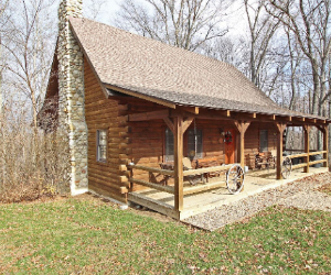 log cabin with long front porch with fence